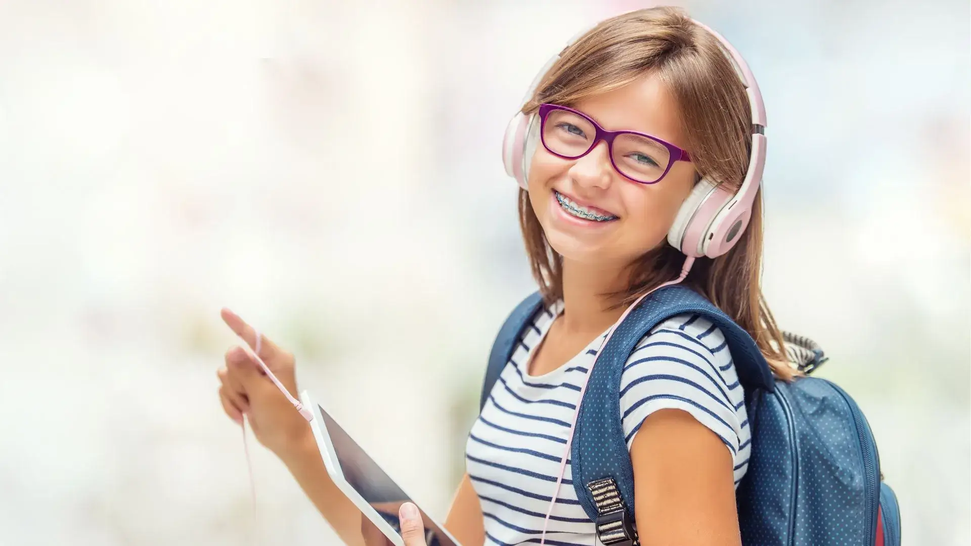 Young girl with braces and headphones smiling, demonstrating healthy smiles and orthodontic treatment for kids.