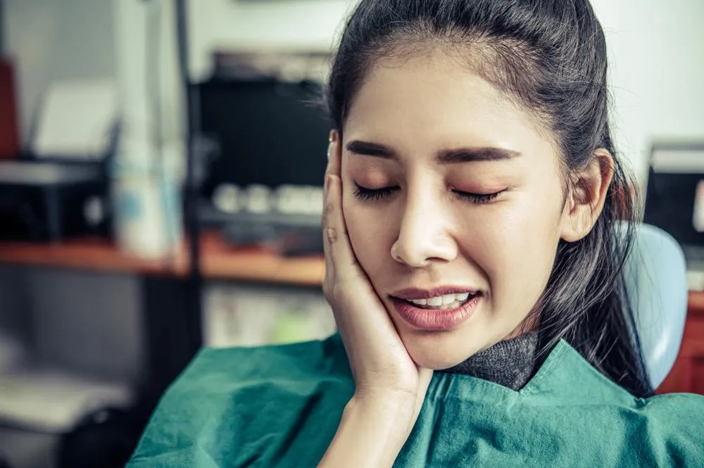 woman with a toothache cupping her cheeks