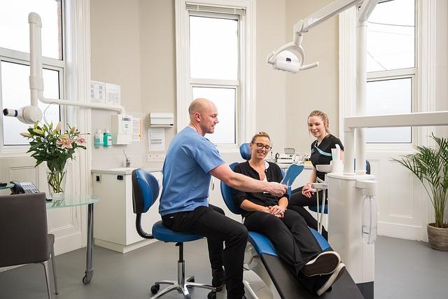 a dentist holding a mirror in front of a patient sitting on the dentist chair