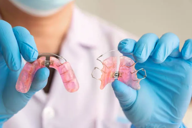 a close-up view of a set of clear and metal retainers placed on a white surface, showcasing their design and structure