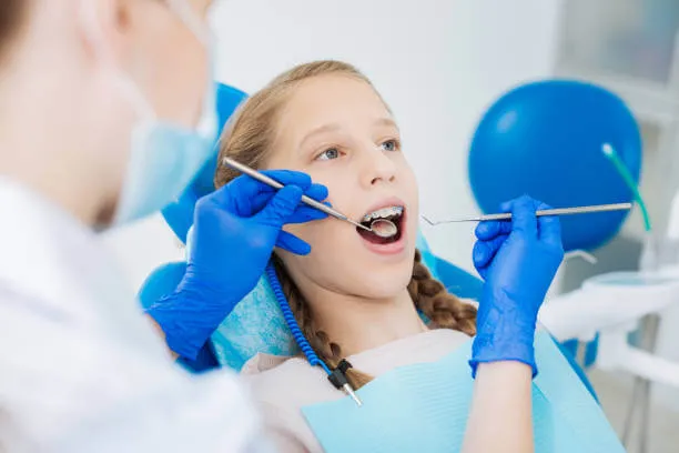 child with braces attending a routine dental visit cleaning and exam