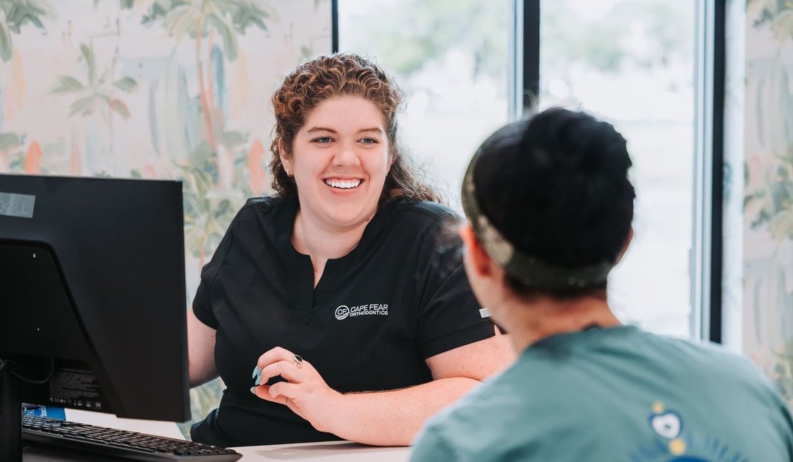 Cape Fear Orthodontics team member reviewing a treatment plan with a smiling visitor